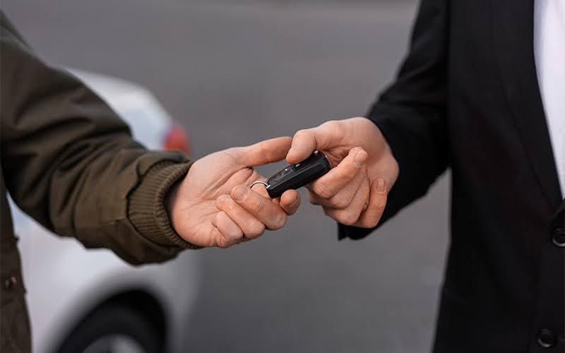 Person Handing Over A Car Key For A Car Lease Agreement